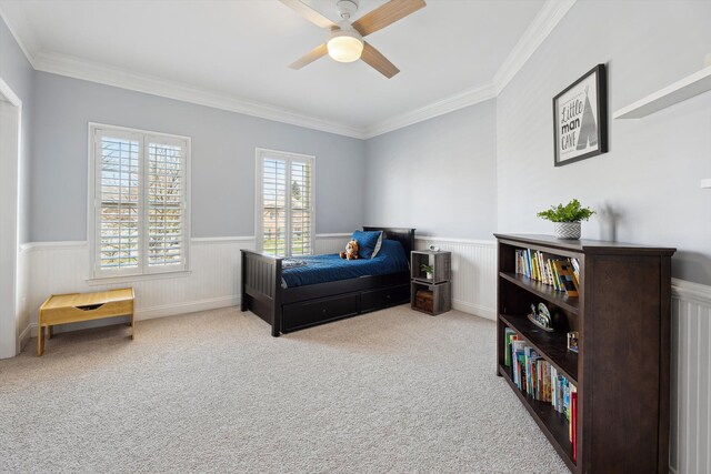 carpeted bedroom featuring a wainscoted wall, ornamental molding, and ceiling fan