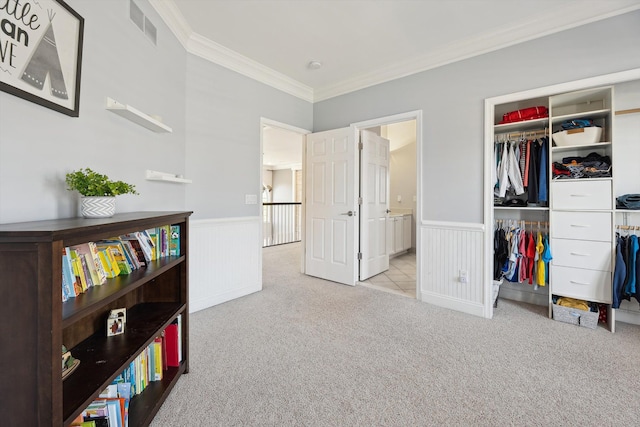 bedroom with carpet flooring, a wainscoted wall, visible vents, ornamental molding, and a closet
