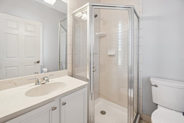 bathroom with vanity, a shower stall, and toilet