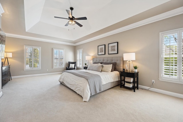 bedroom featuring baseboards, a raised ceiling, light carpet, and multiple windows