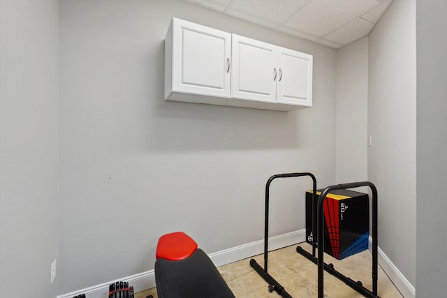 workout area with baseboards and a drop ceiling