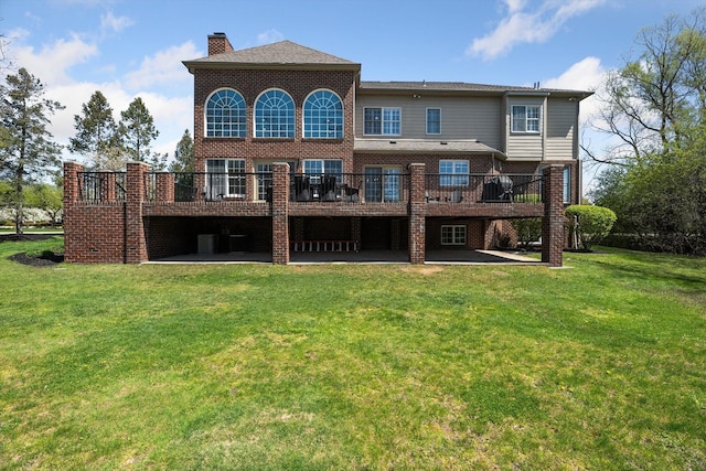 back of property featuring a lawn, brick siding, a wooden deck, and a patio