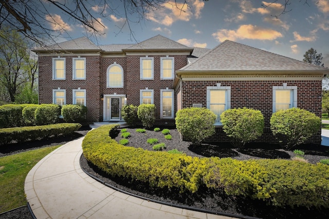 view of front facade with brick siding and a shingled roof
