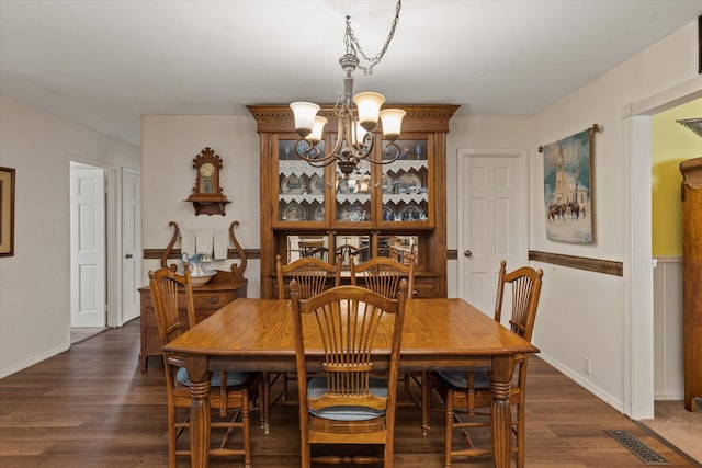 dining space with baseboards, a notable chandelier, visible vents, and dark wood-style floors