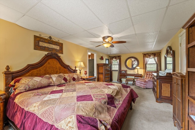 carpeted bedroom featuring a drop ceiling and ceiling fan