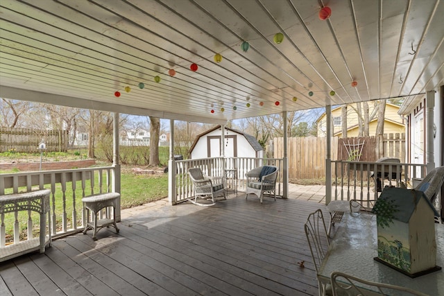 wooden terrace featuring an outbuilding, a shed, and a fenced backyard
