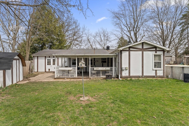 rear view of property with a storage shed, fence, a patio area, a lawn, and an outdoor structure