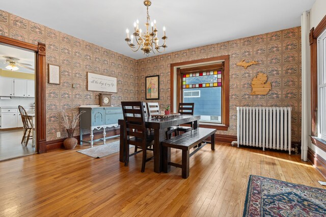 265 Bailey Ave, South Haven, MI 49090 - dining area with radiator, wallpapered walls, light wood-type flooring, and a notable chandelier