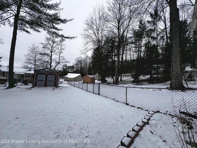 17669 Lake Dr, Barryton, MI 49305 - yard layered in snow featuring a storage unit, fence, and an outbuilding