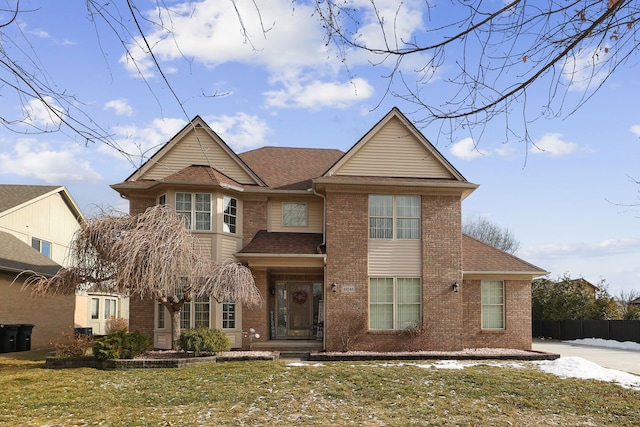 traditional-style home with fence, brick siding, and roof with shingles