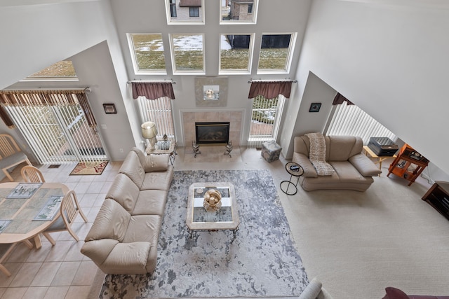 living room with tile patterned flooring, a towering ceiling, and a fireplace