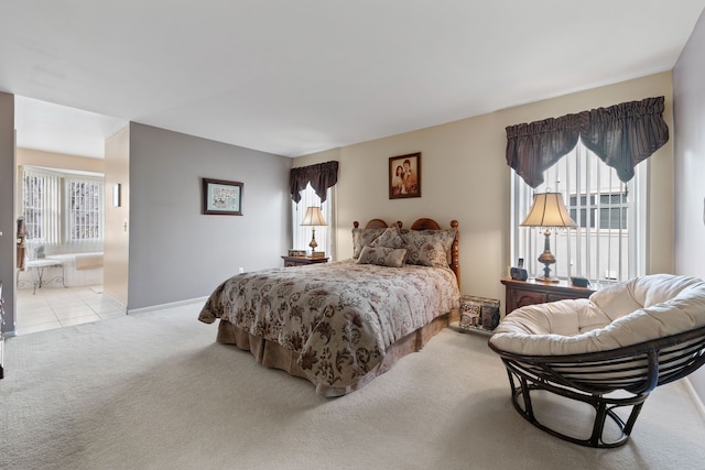 carpeted bedroom with ensuite bath, baseboards, and multiple windows