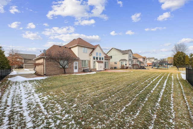 rear view of house featuring fence, a lawn, brick siding, and a residential view