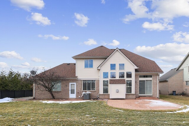 rear view of property featuring central AC unit, a yard, a patio, brick siding, and roof with shingles