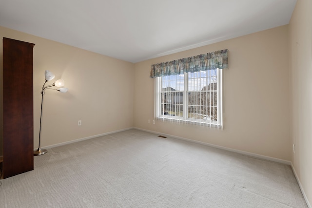 carpeted empty room featuring baseboards and visible vents