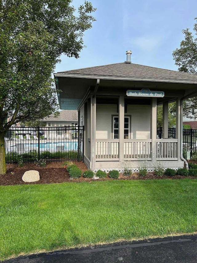 view of front of home with fence, a shingled roof, a fenced in pool, and a front yard
