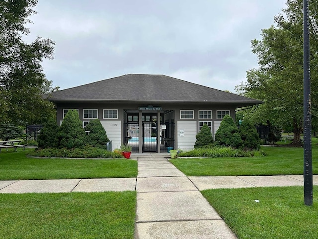 view of front of home featuring roof with shingles, a front yard, and fence