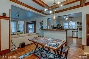 dining space with a ceiling fan, beam ceiling, wood finished floors, and coffered ceiling