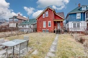 rear view of property featuring a yard and fence