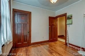 unfurnished bedroom featuring baseboards, ornamental molding, and wood finished floors