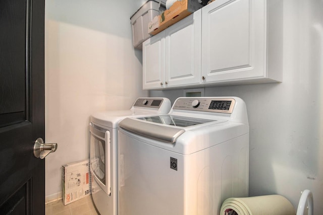 clothes washing area with baseboards, washer and clothes dryer, and cabinet space