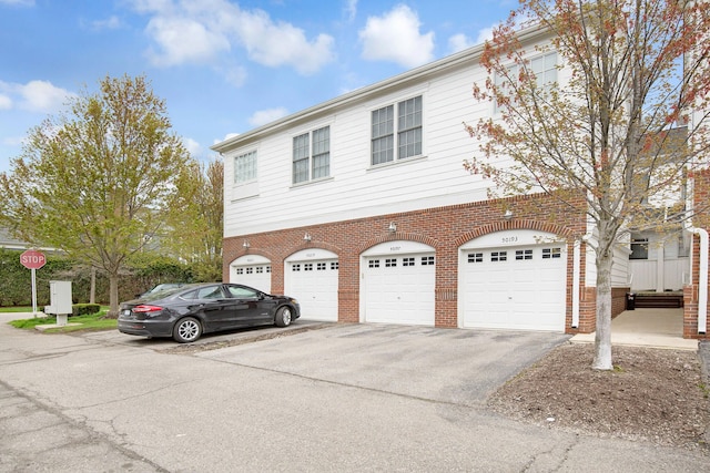 view of front of home featuring a garage, driveway, and brick siding