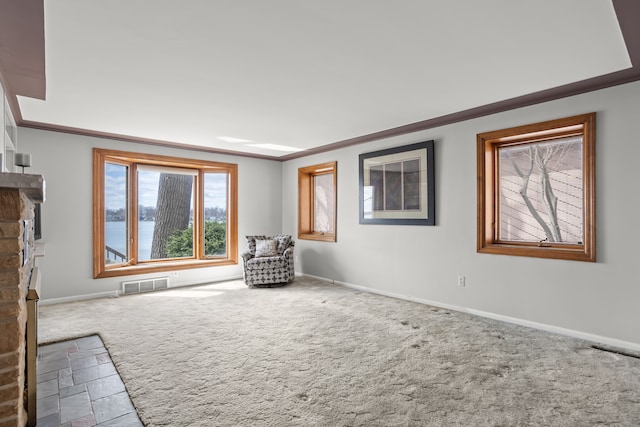 unfurnished room featuring visible vents, crown molding, a fireplace, carpet floors, and baseboards