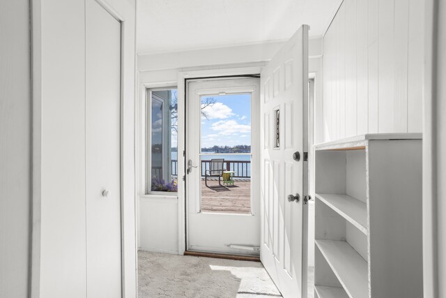 doorway with ornamental molding and carpet flooring