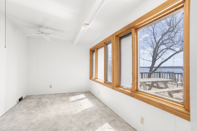 carpeted spare room with a water view, a ceiling fan, and beam ceiling