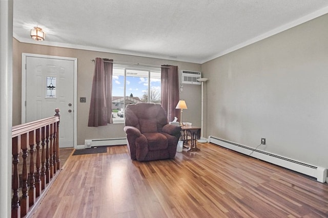 living area featuring baseboard heating, wood finished floors, a wall unit AC, a textured ceiling, and baseboards