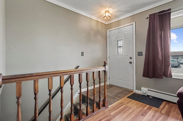 foyer with baseboard heating, wood finished floors, baseboards, and crown molding