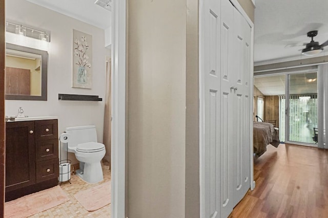 bathroom featuring toilet, vanity, ceiling fan, wood finished floors, and ensuite bathroom