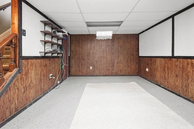 finished below grade area with wood walls, stairs, and a drop ceiling