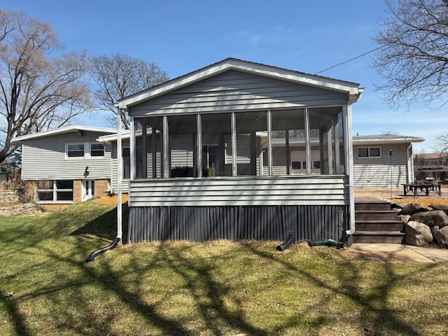 rear view of house with a sunroom and a yard