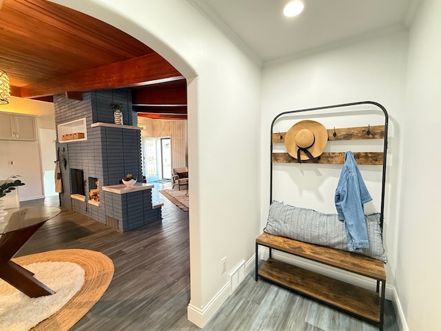 interior space with beamed ceiling, wood finished floors, a brick fireplace, and arched walkways