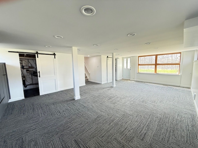 below grade area featuring a barn door, stairs, dark carpet, baseboards, and recessed lighting