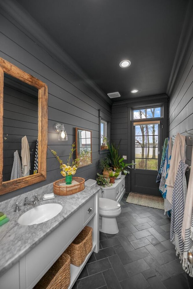 46815 Elizabeth Ln, Decatur, MI 49045 - bathroom featuring wooden walls, toilet, vanity, and recessed lighting