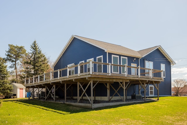 rear view of property featuring a deck, a shed, a lawn, and an outdoor structure