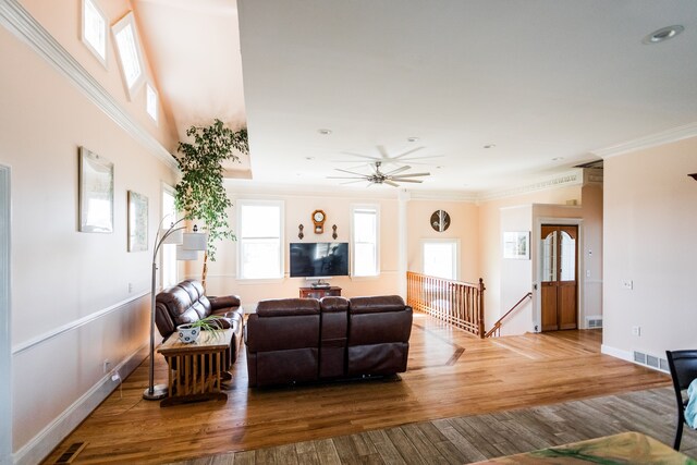 living area featuring ornamental molding, plenty of natural light, wood finished floors, a ceiling fan, and baseboards