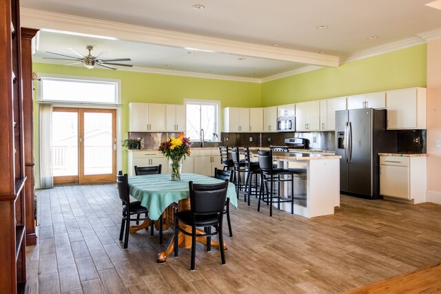 dining area featuring light wood-style flooring, ceiling fan, and crown molding