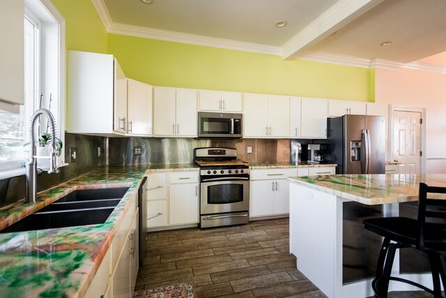 kitchen with appliances with stainless steel finishes, crown molding, a kitchen breakfast bar, and white cabinets