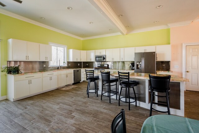 kitchen with stainless steel appliances, crown molding, a kitchen island, white cabinetry, and decorative backsplash