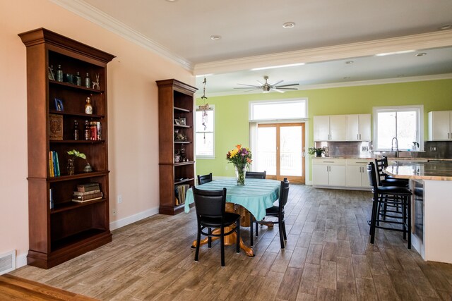 dining area with dark wood-style floors, crown molding, ceiling fan, and baseboards