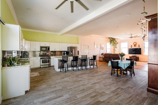 dining space featuring a ceiling fan, light wood-style flooring, and ornamental molding