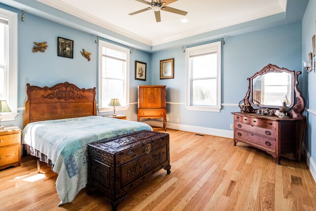 bedroom featuring light wood finished floors, multiple windows, ornamental molding, and ceiling fan