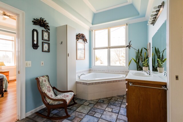 bathroom with a bath, vanity, a tray ceiling, crown molding, and stone tile floors