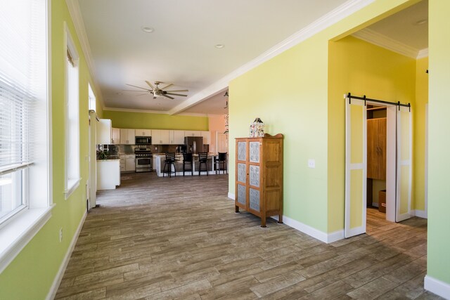 hallway featuring a barn door, crown molding, wood finished floors, and baseboards