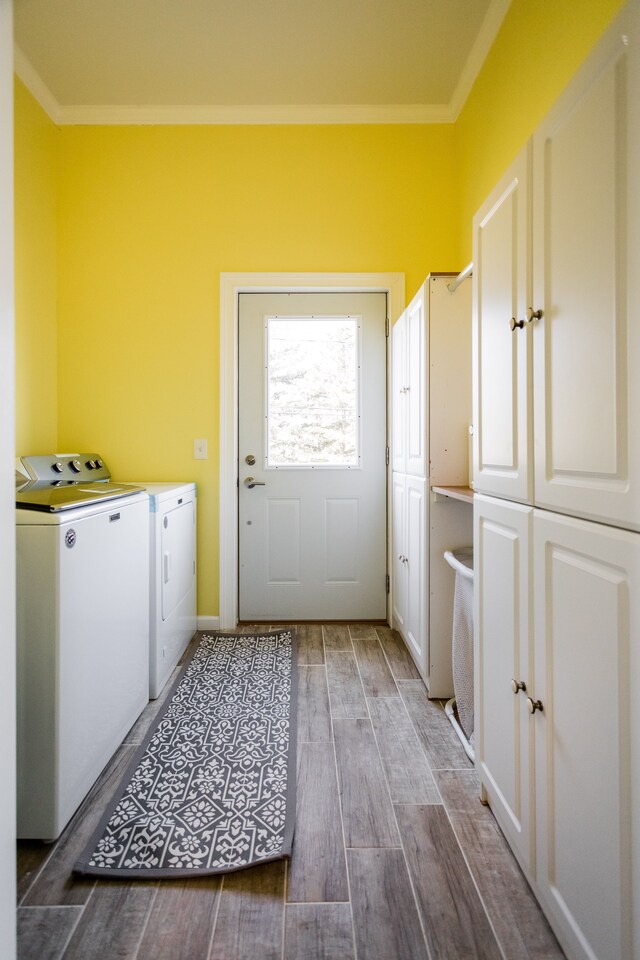 laundry area with ornamental molding, cabinet space, washing machine and clothes dryer, and wood finished floors