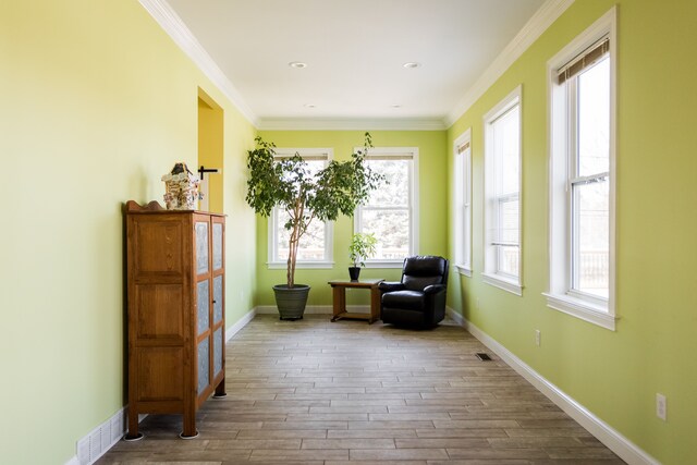 sitting room featuring healthy amount of natural light, crown molding, wood finished floors, and baseboards