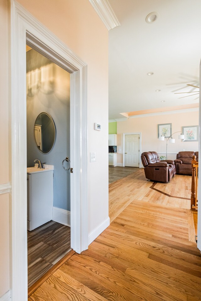 corridor with ornamental molding, wood finished floors, and baseboards